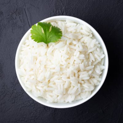 Boiled rice in a bowl on black stone background.